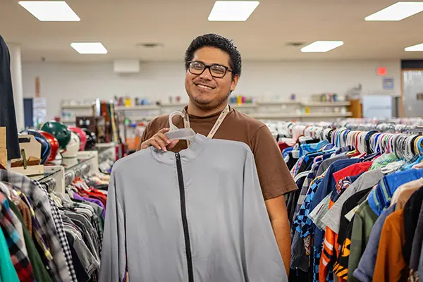 Individual supported by PSW displaying donated clothing at Value Village Thrift Store.
