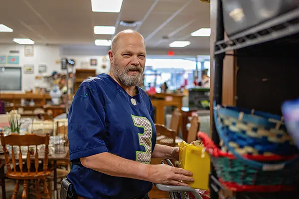 Individual supported by PSW organizing donated household items at Value Village Thrift Store.